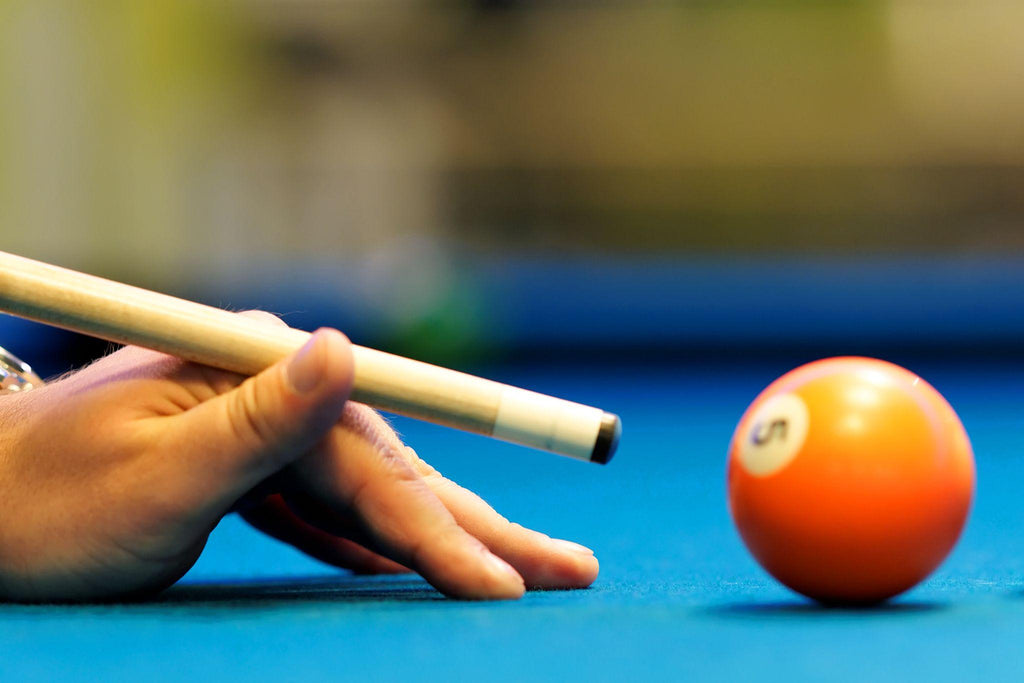 man's hand with cue playing pool